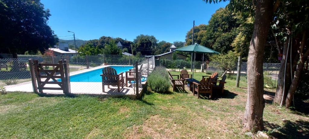 einen Zaun um einen Pool mit Stühlen und einem Sonnenschirm in der Unterkunft Cabañas y departamentos Sol y Luna in Villa General Belgrano
