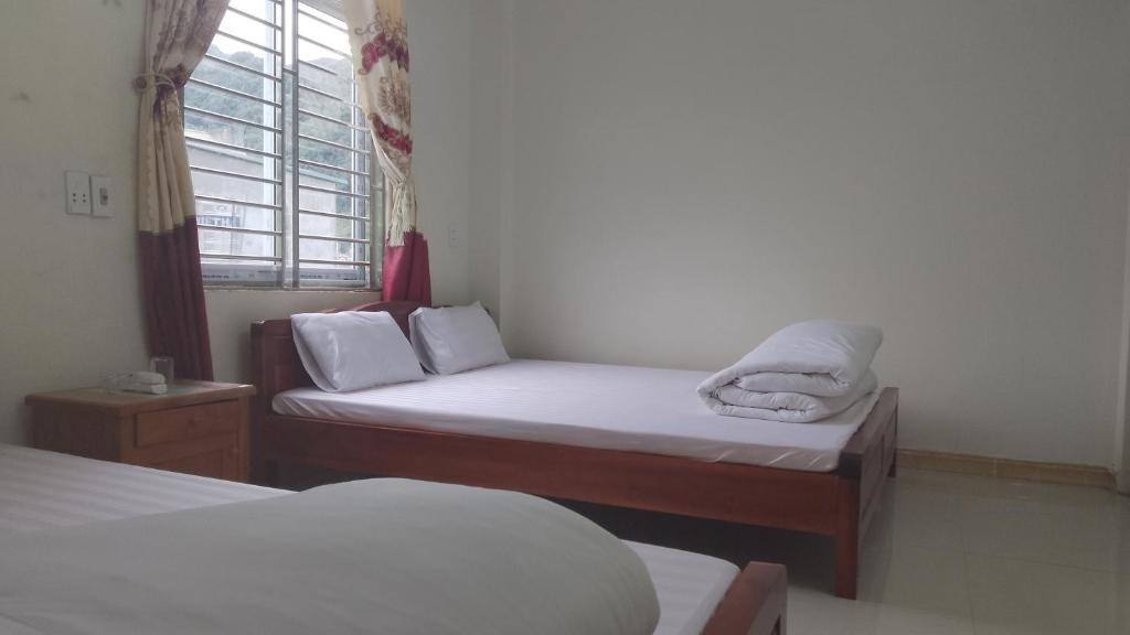 a room with two beds and a window at Nhà nghỉ Ngọc Ánh in Dồng Văn