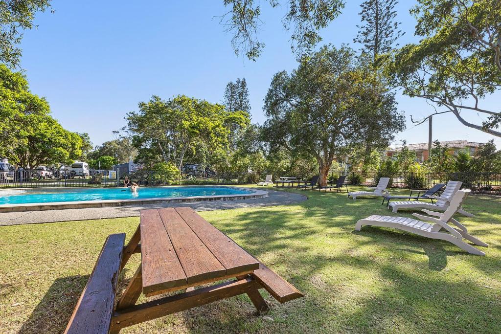 a picnic table and chairs next to a swimming pool at Reflections Mylestom - Holiday Park in Mylestom