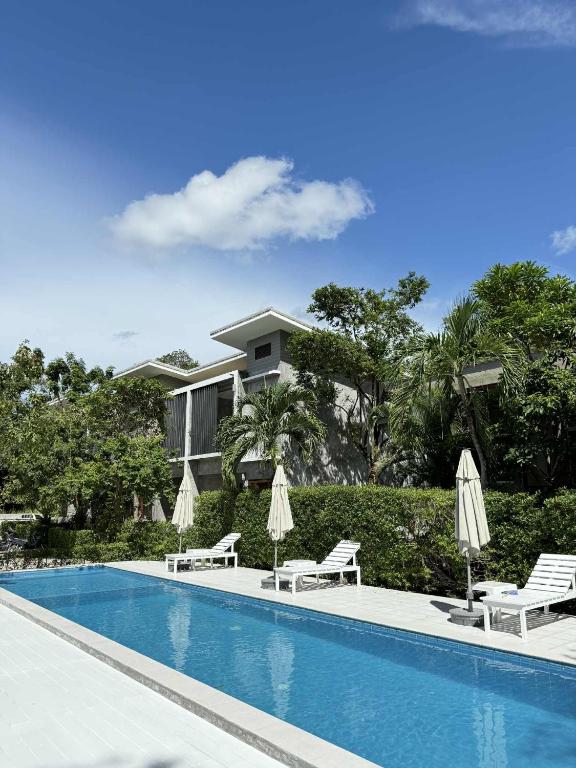 a swimming pool with chairs and umbrellas in front of a house at The Rinya Hotel Koh Phangan in Thong Sala