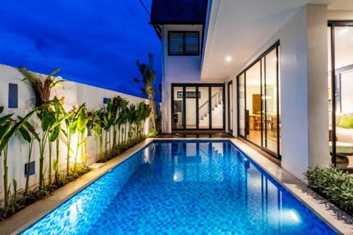 a swimming pool in front of a house at Asri loka villa in Ubud