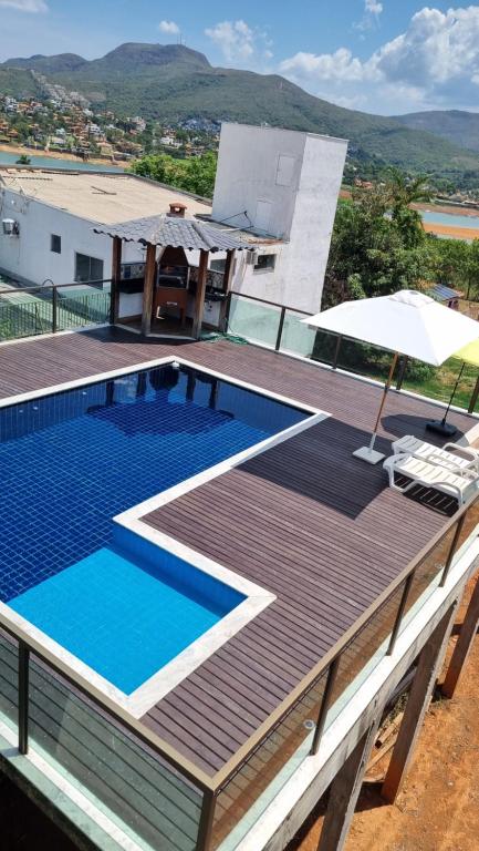 a house with a swimming pool and an umbrella at RECANTO BRENDA - Casa Luxo Capitólio com Vista pro lago, Escarpas e MorroChapeu in Capitólio