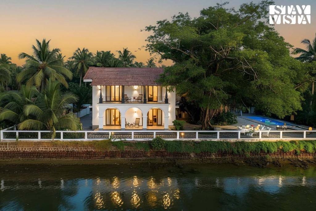 una casa con un río delante de ella en StayVista at Di Mora by the Sea with Lawn & Pool, en Baga