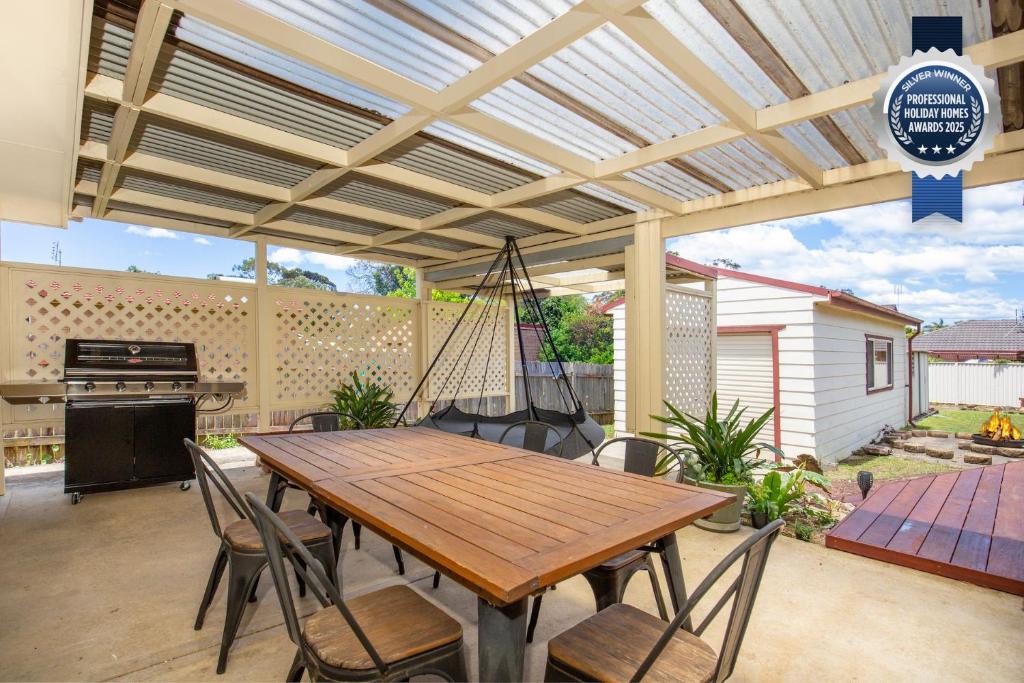 a patio with a wooden table and chairs at Wagtails Pet Friendly 10 Mins Walk to Beach in Culburra Beach