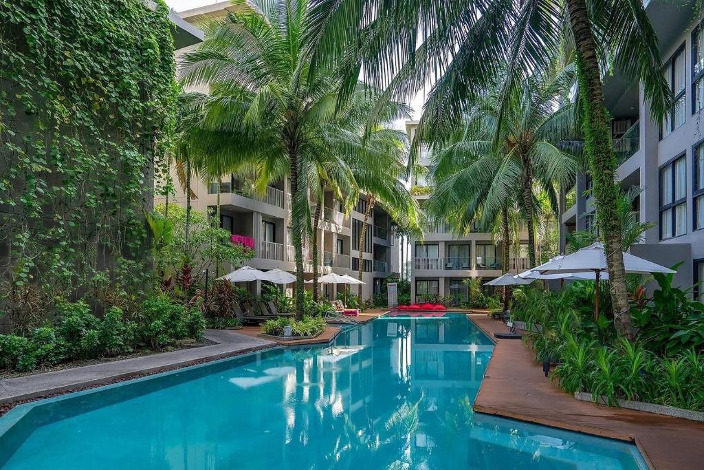 Una piscina con palmeras y un edificio. en Diamond apartaments 700m BangTao beach, en Bang Tao Beach
