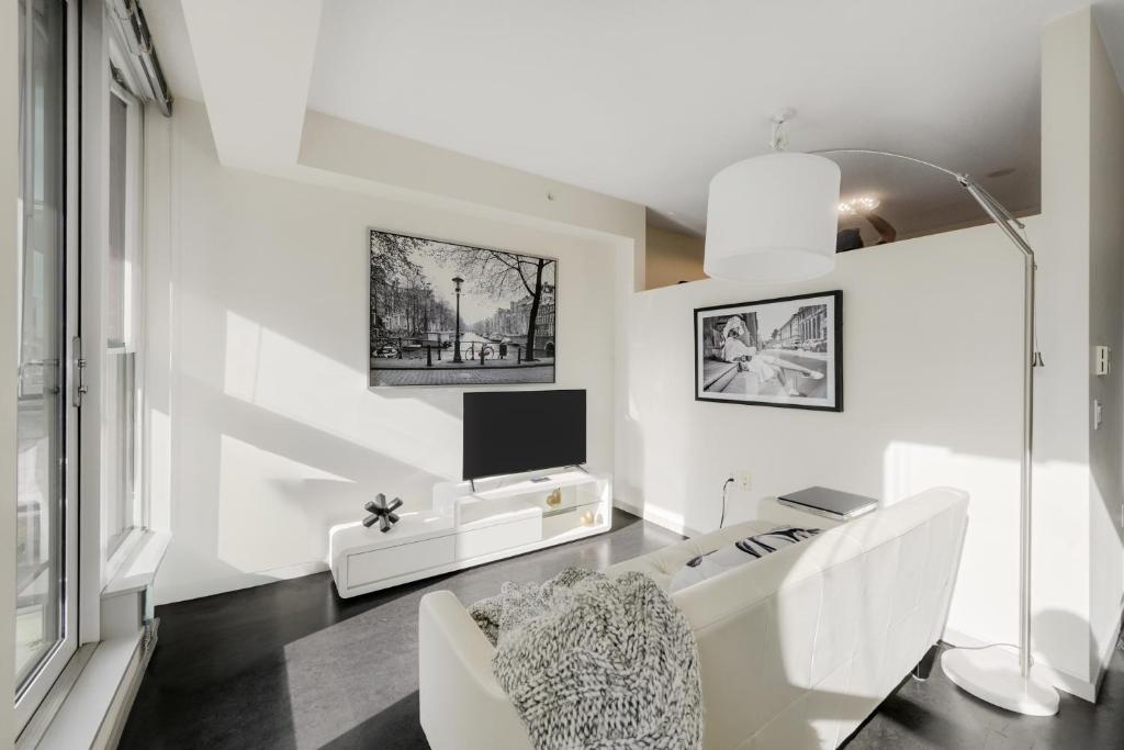 ビクトリアにあるChic & Modern Apartment In The Heart Of Downtownの白いリビングルーム(白いソファ、テレビ付)