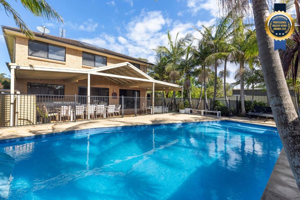 a large blue swimming pool in front of a house at Water Lane - Swimming Pool - 4 Mins Walk to Bay in Callala Bay