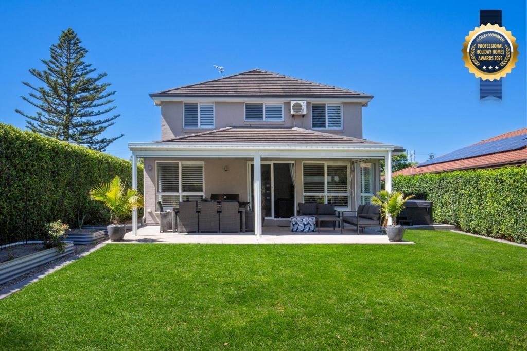 a house with a lawn in front of it at Bluewater Jervis Bay - Pet Friendly Luxury with Spa - 5 Mins Walk to Beach in Callala Beach