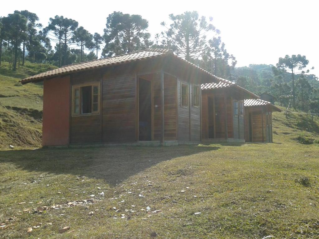 una pequeña casa de madera en un campo de hierba en Pousada Caverna Rio dos Bugres, en Urubici