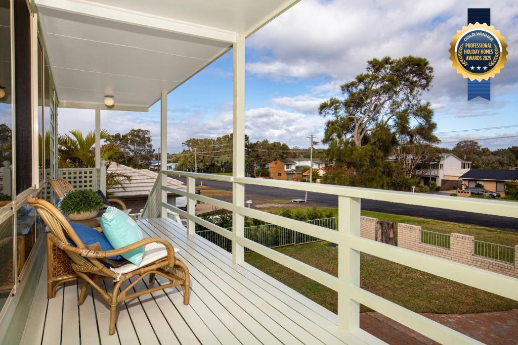 une femme assise dans une chaise en osier sur un porche dans l'établissement Palms I Pet Friendly I 2 Mins to Beach, à Culburra Beach