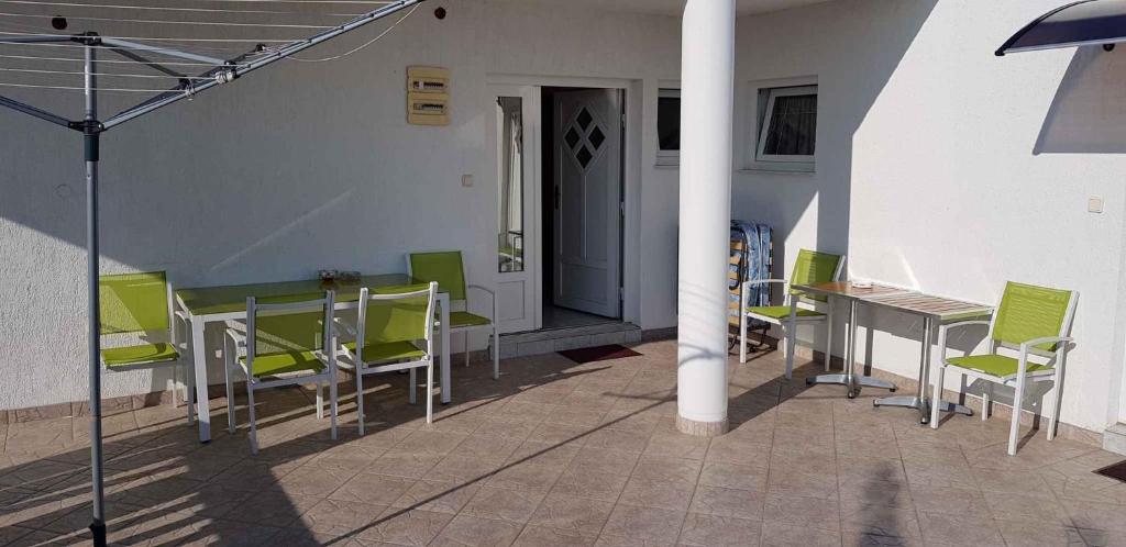 a patio with green chairs and a table and a pole at Apartments in Pirovac 34905 in Pirovac