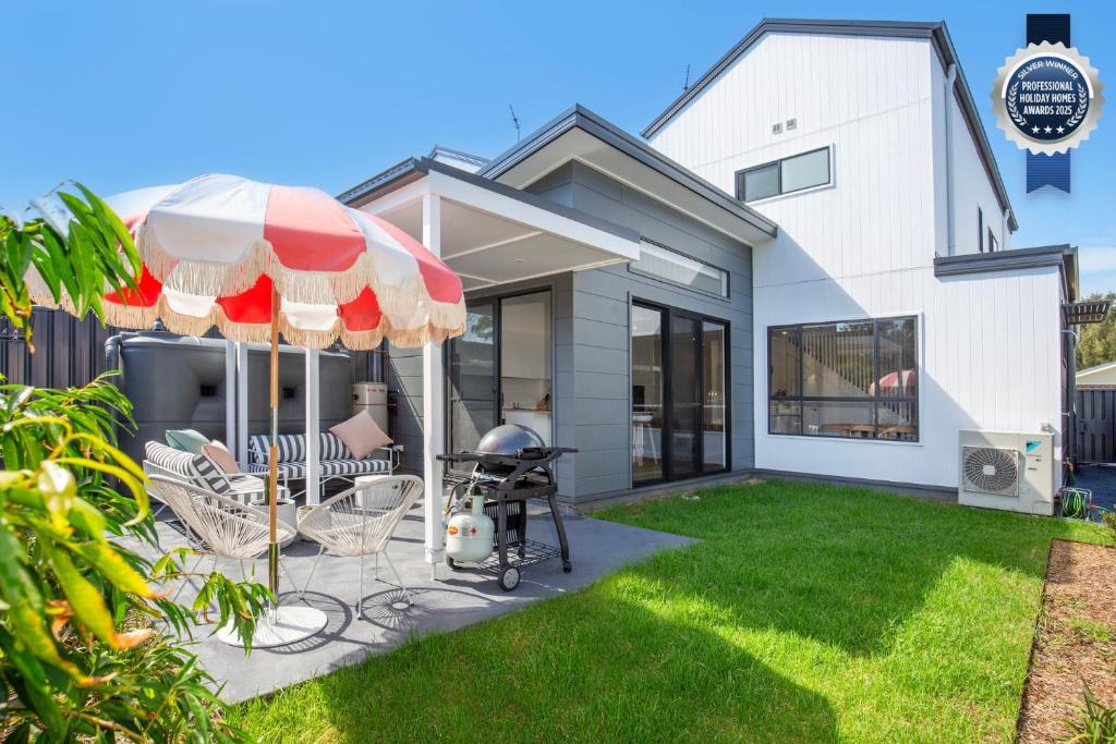 a house with a patio with a grill and an umbrella at Burra Beachy - Pet Friendly - 5 Mins Walk to Beach in Culburra Beach