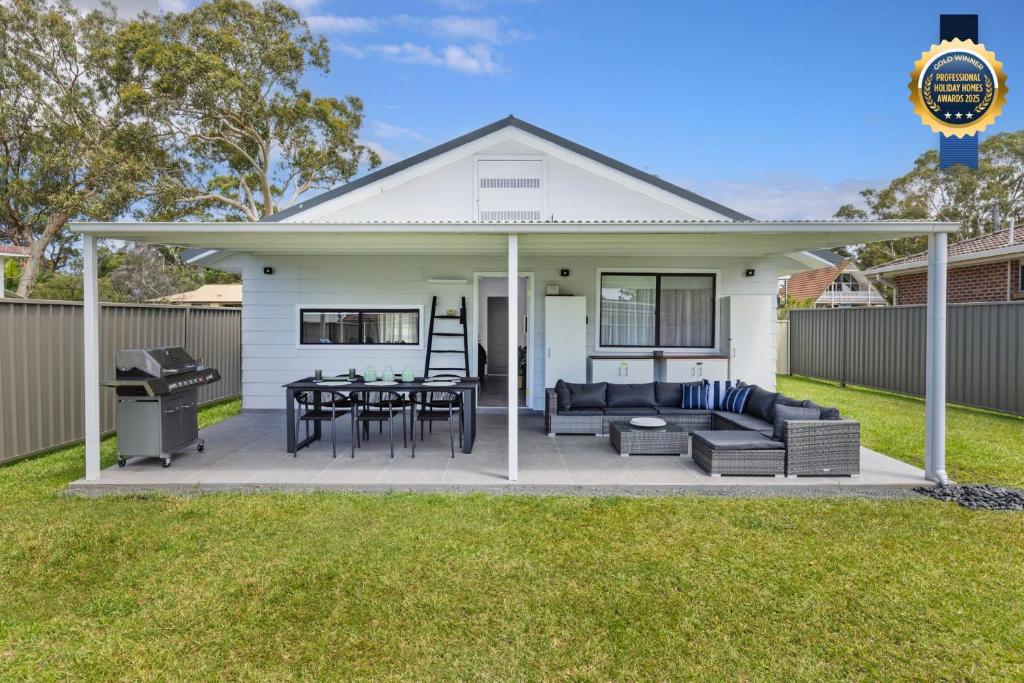 a white house with a patio and a grill at Serendipity Stays Jervis Bay - 5 Mins Walk to Beach in Sanctuary Point
