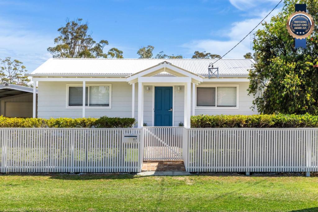 a white house with a white fence at Indigo Pet Friendly 5 Mins Walk to Bay in Callala Bay