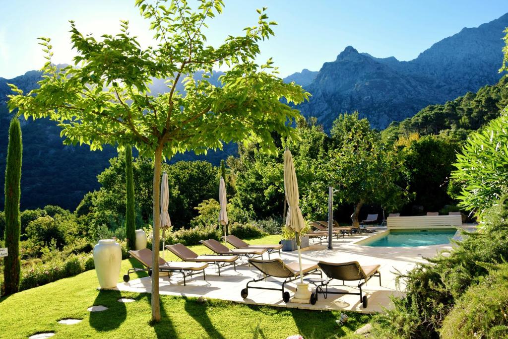 a group of chairs and umbrellas next to a pool at Cas'Anna Lidia - Hôtel De Charme in Feliceto