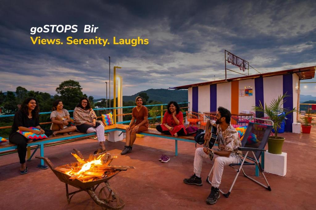 um grupo de pessoas sentadas à volta de uma lareira num pátio em goSTOPS Bir, Landing Site em Bir