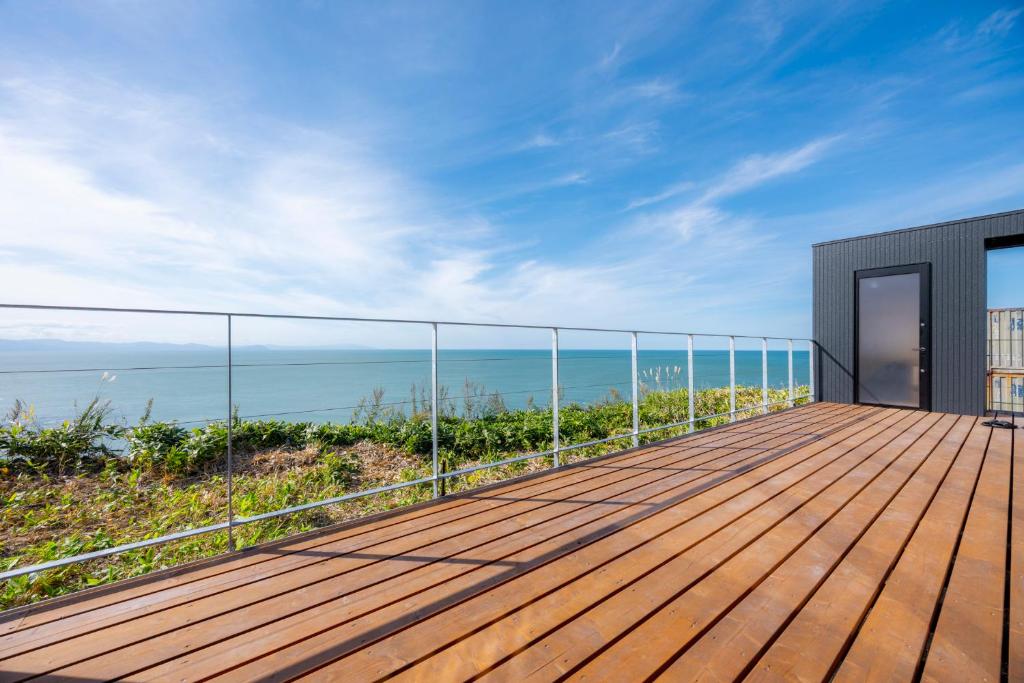 een houten terras met uitzicht op de oceaan bij the SHIHACHI 