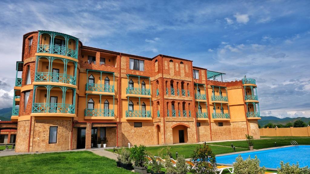 a large brick building with a pool in front of it at Burki Castle & Cellar in Kvareli