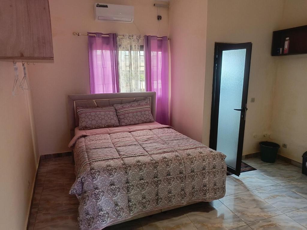 a bedroom with a bed and a window with pink curtains at Très Bel Appartement Moderne-1 Appartement Nuptial in Libreville