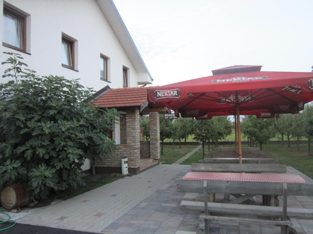 a picnic table with a red umbrella in front of a building at Pansion Laktaši in Laktaši