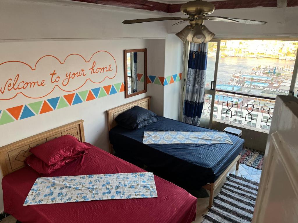 two beds in a room with a balcony at Aisha guesthouse in Aswan