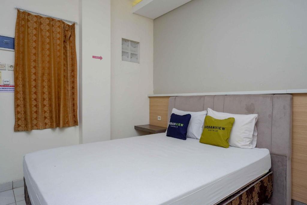 a bedroom with a bed with three pillows on it at Urbanview Hotel Double Tree near RSUD Margono Purwokerto in Purwokerto
