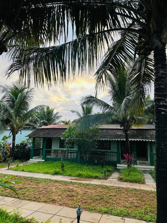 a house with palm trees in front of it at Golden Pearl Beach Resort in Baga