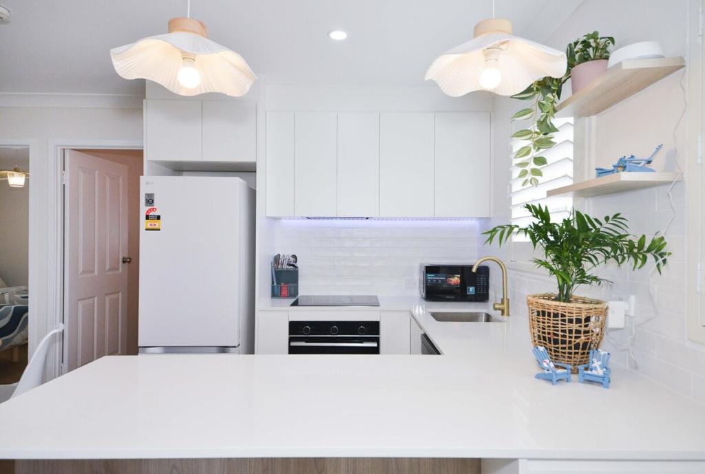 a white kitchen with a white refrigerator and a plant at Haven at Redcliffe - your stay on the Peninsula in Redcliffe