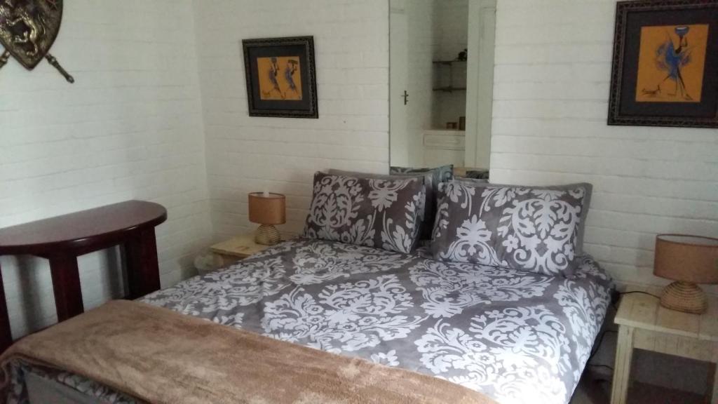 a bedroom with a bed with a gray and white comforter at The Budget Inn in Bloemfontein