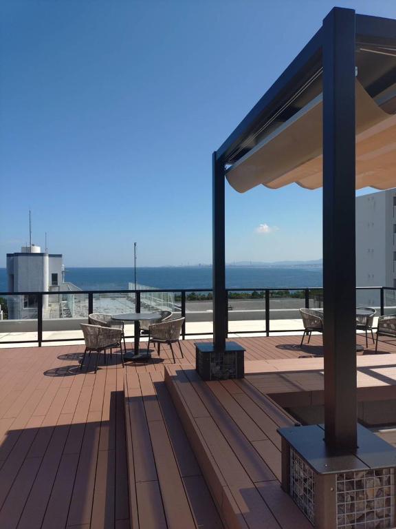 eine Terrasse mit Tisch und Bänken auf einem Dach in der Unterkunft BEPPU Sento in Beppu