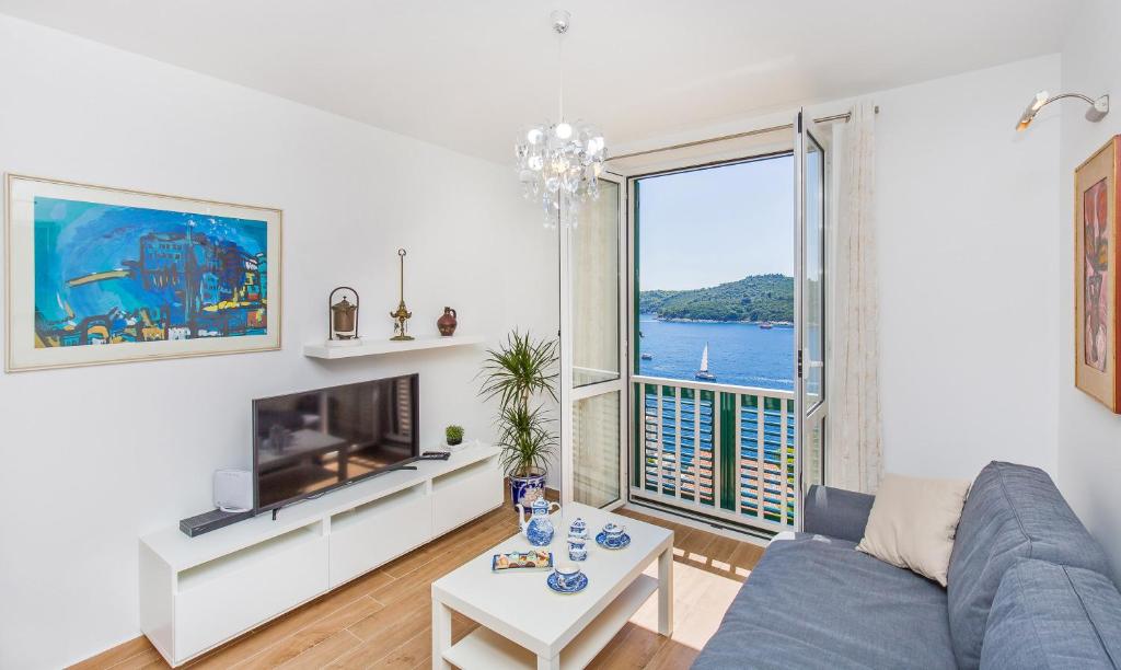 a living room with a blue couch and a large window at Apartment Majestic in Dubrovnik
