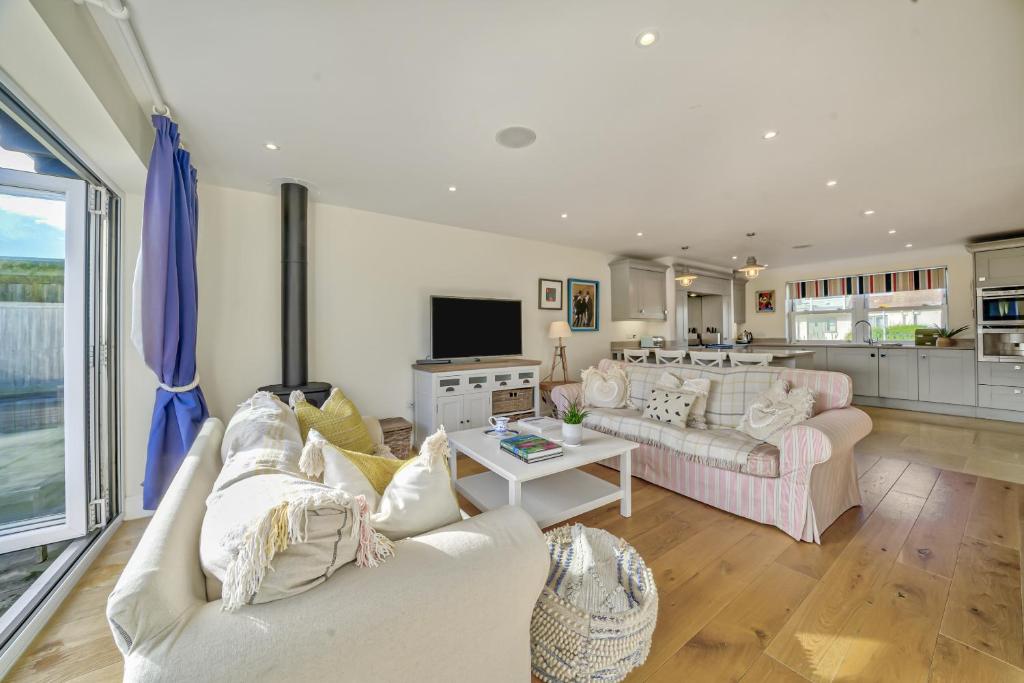 a living room with two couches and a kitchen at Shore View - East Wittering in East Wittering