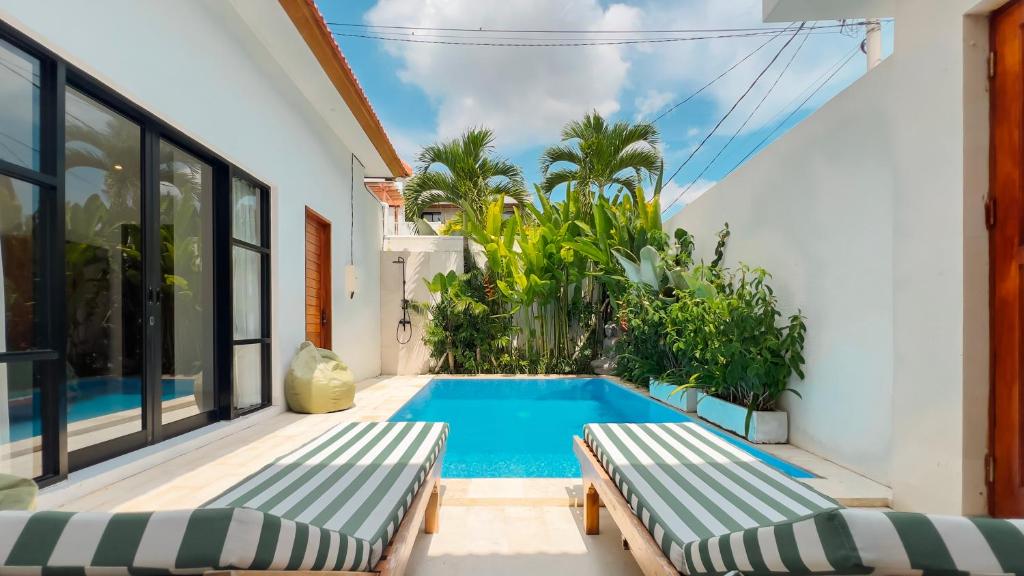 DalungにあるCosy 2bed/2bath villa 5 min to beachの家の隣にベンチ2つ付きのスイミングプール