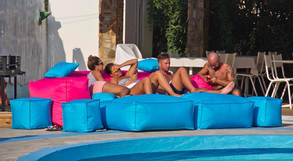 a group of people sitting on inflatable beds by a pool at Macedon in Limenas