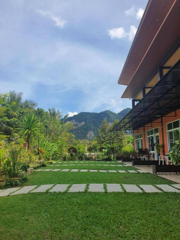 a courtyard of a building with grass and mountains at Khao Sok Country Resort in Khao Sok National Park