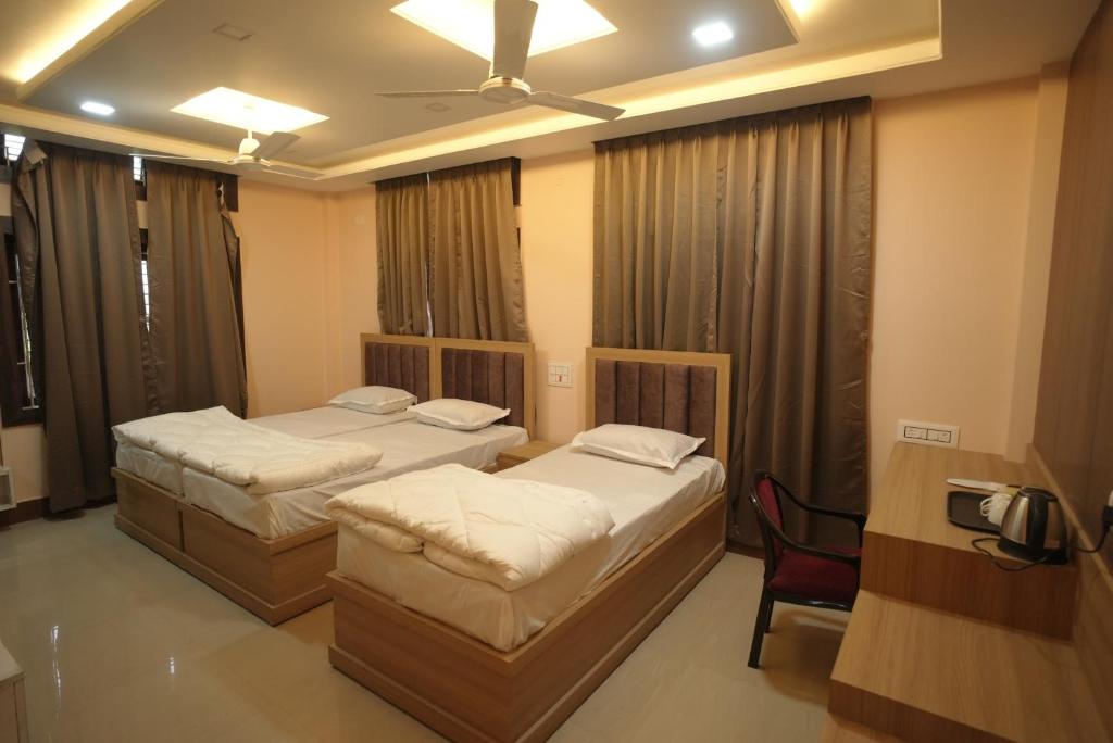 a bedroom with two beds and a chair in it at Aroma Homes in North Lakhimpur