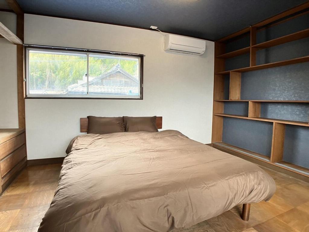a bedroom with a large bed and a window at イマヅのかくれ家 in Fukuoka