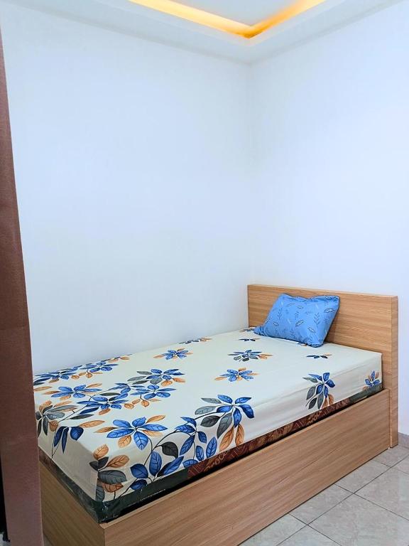 a bedroom with a bed with blue flowers on it at Casa Bella Homestay in Palembang