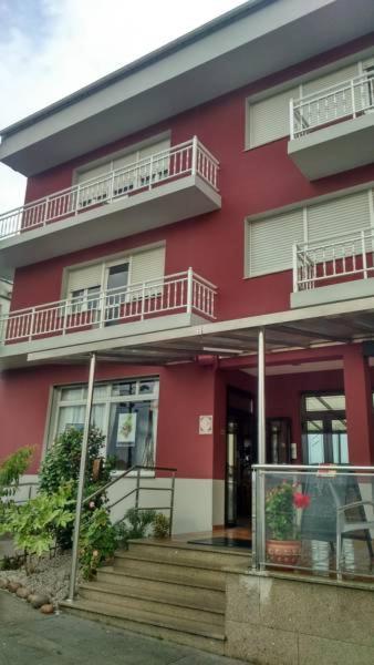 a red building with stairs and balconies on it at Pensión Vázquez in Vimianzo