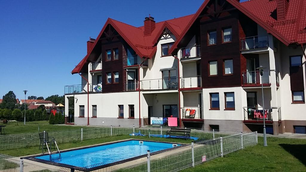 a building with a swimming pool in front of it at Apartament Latarnia in Jastrzębia Góra