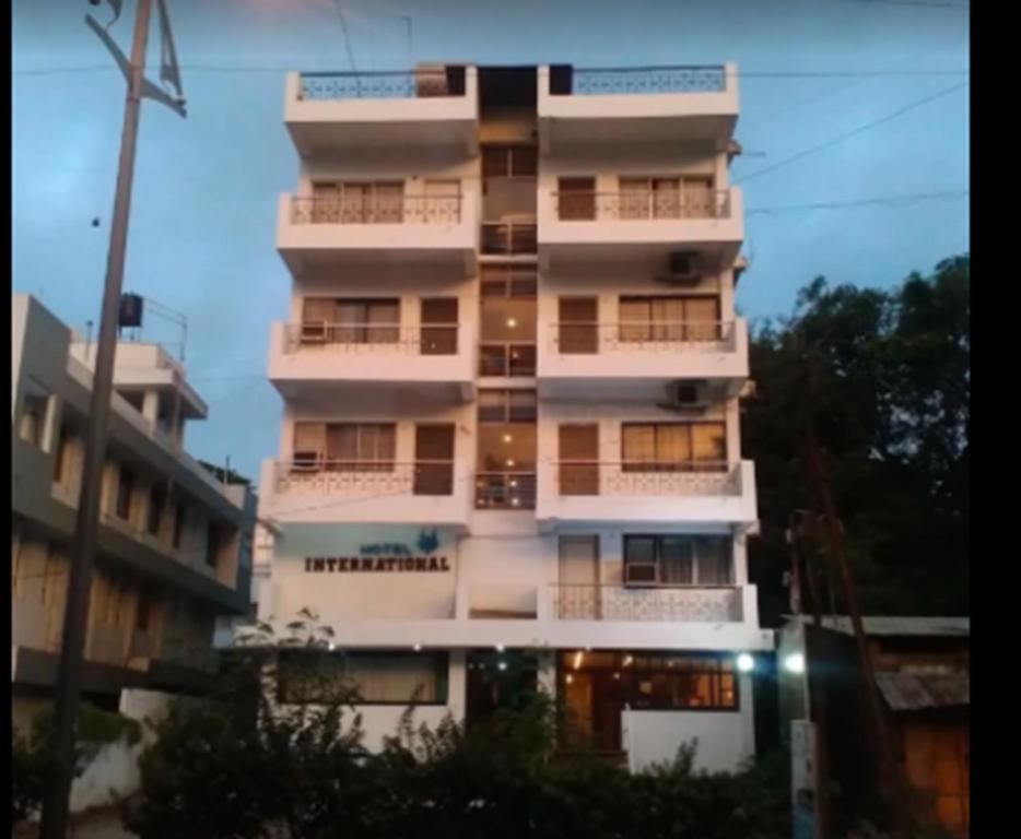 a tall white apartment building with windows at Hotel International, Kolhapur in Kolhapur