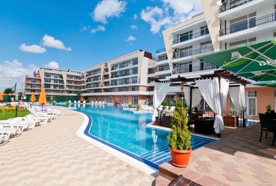 una piscina en un resort con sillas y sombrillas en Grand Kamelia apartments, en Sunny Beach