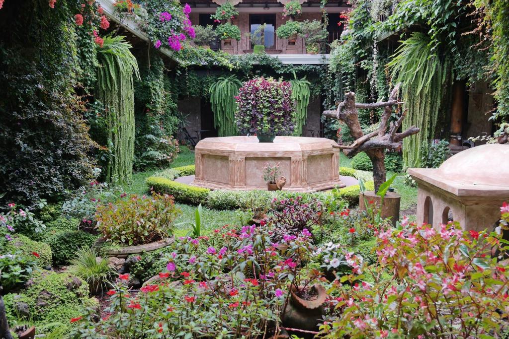 a garden with a fountain and many flowers at Hotel Genessis in Antigua Guatemala