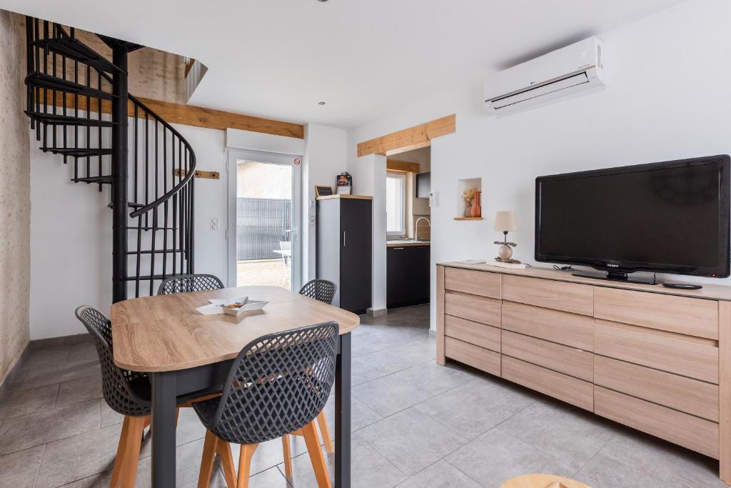 a living room with a television and a table and chairs at Gîte Le Clos Controis in Le Controis En Sologne