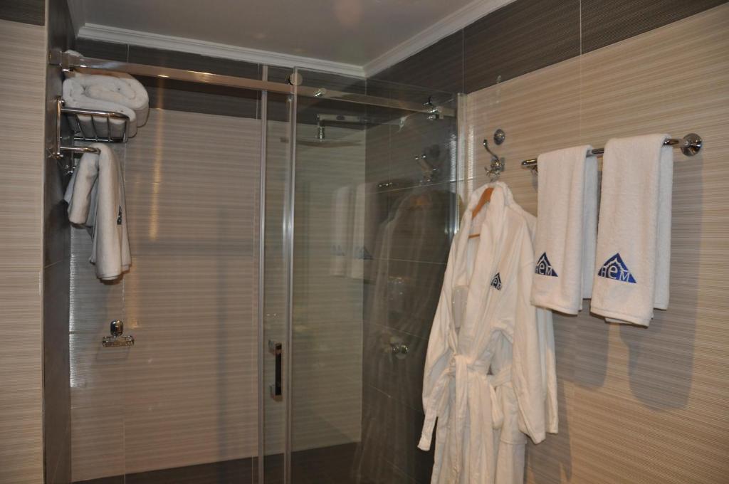 ein Bad mit einer Dusche und weißen Handtüchern an der Wand in der Unterkunft Hotel Emilio Moretti in El Aaiún