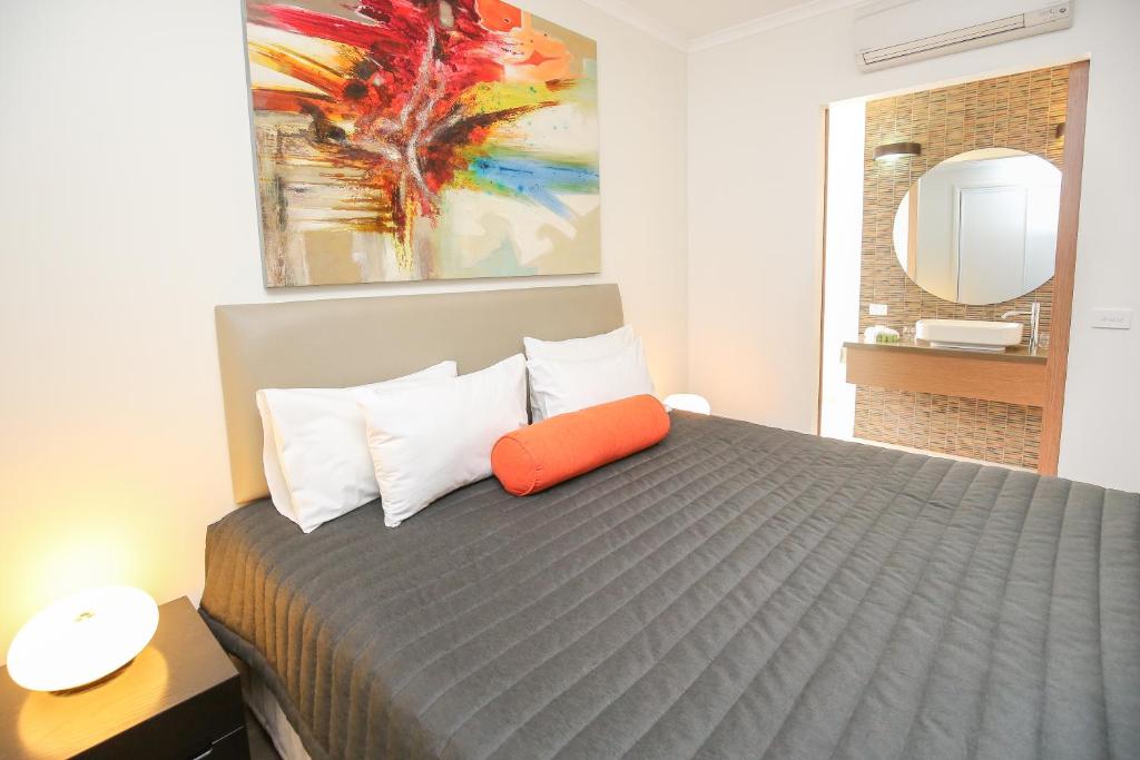a bedroom with a bed with an orange pillow on it at Indulge Apartments - Ontario in Mildura