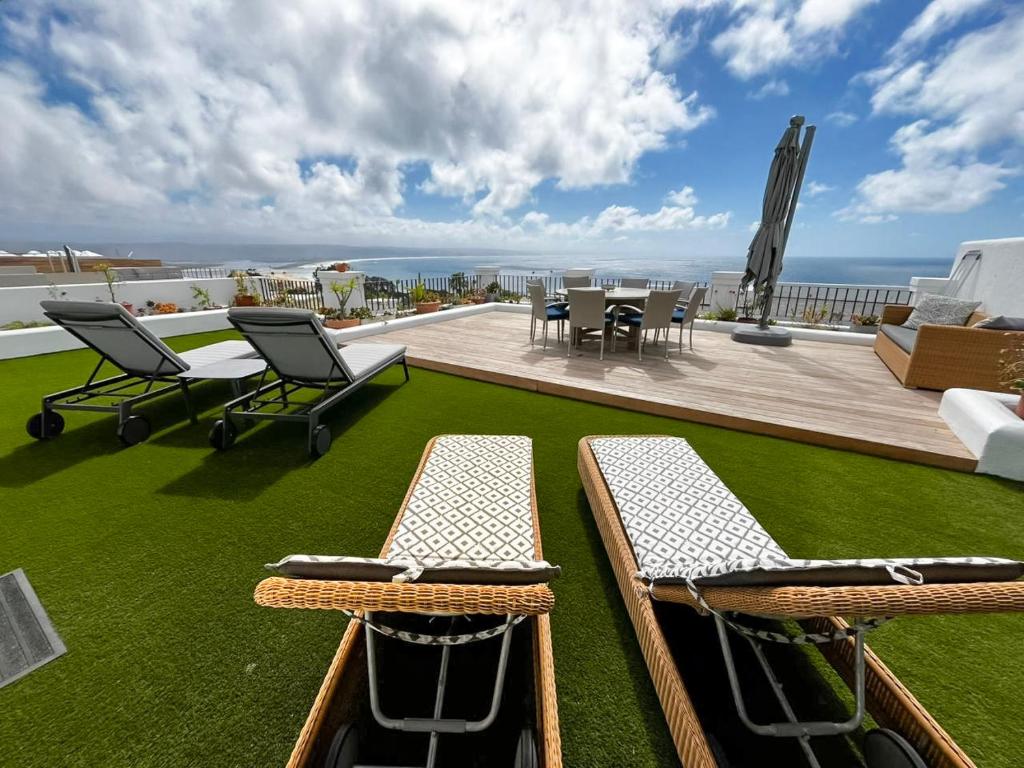 a balcony with two chairs and a table on the grass at Hill Penthouse Plett - Best On Top in Plettenberg Bay