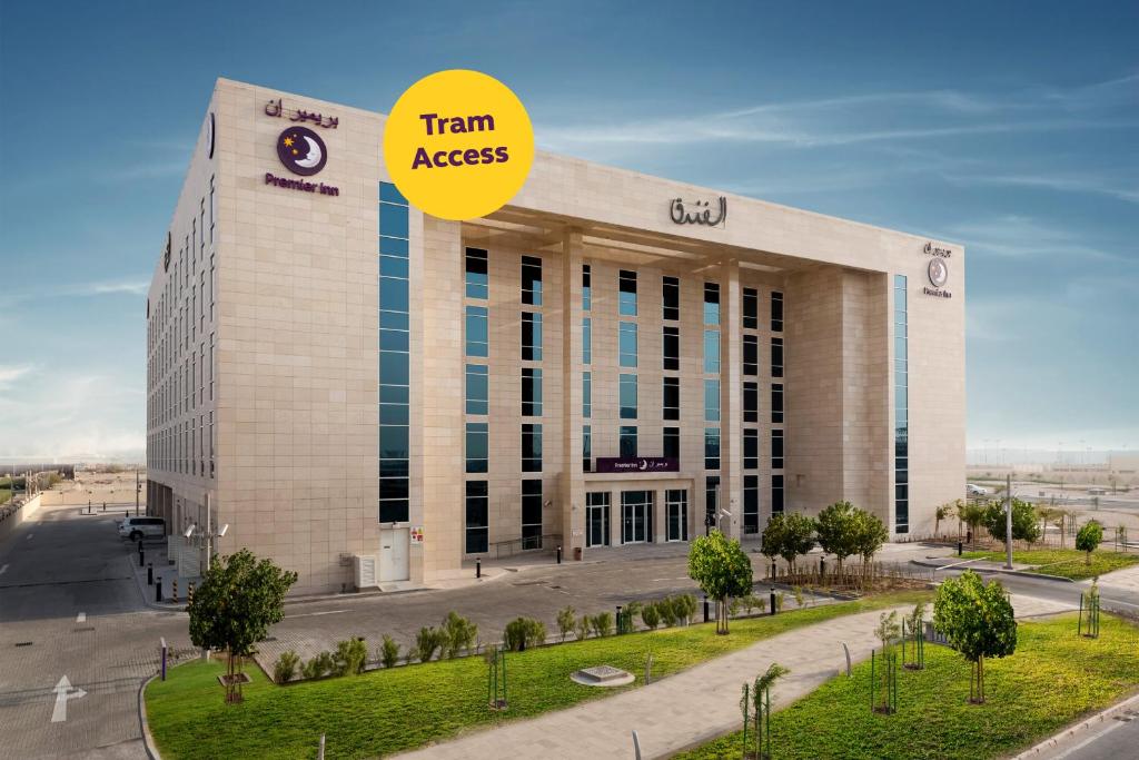 a building with a yellow sign on top of it at Premier Inn Doha Education City in Doha