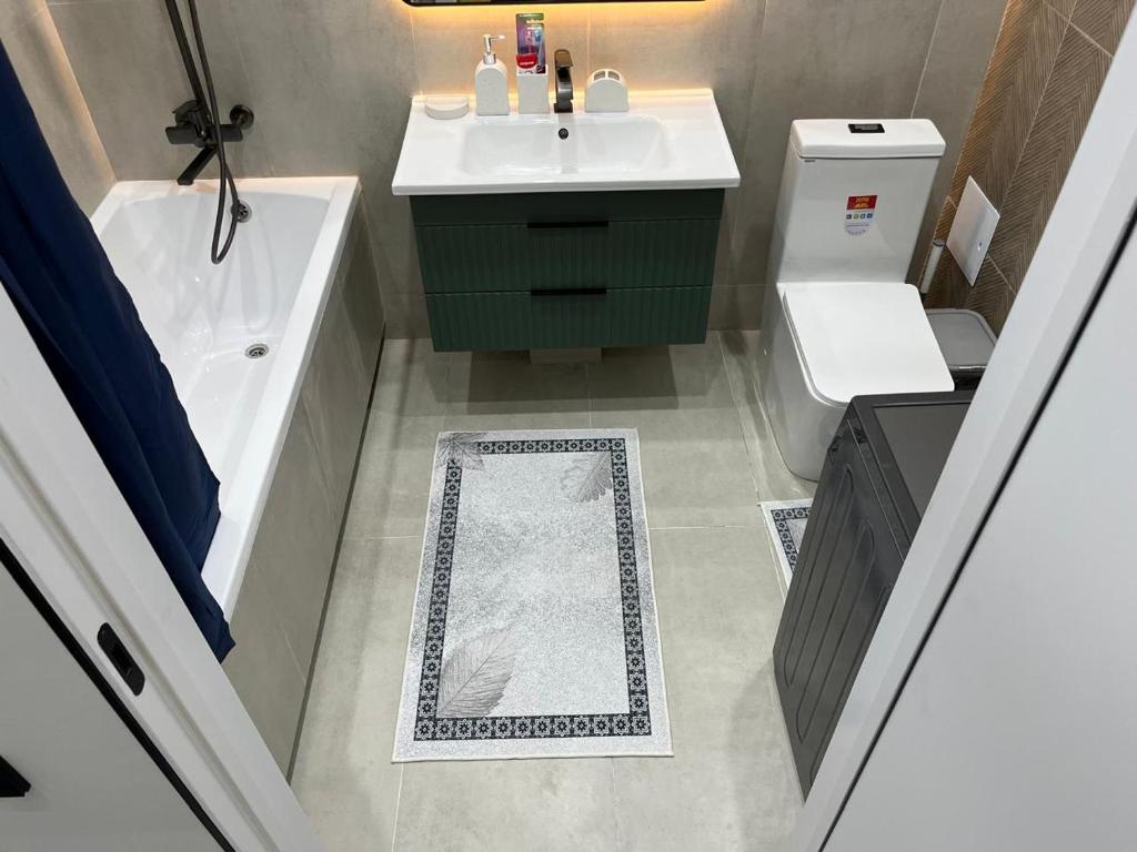 a bathroom with a sink and a tub and a toilet at Elexus Estate in Astana