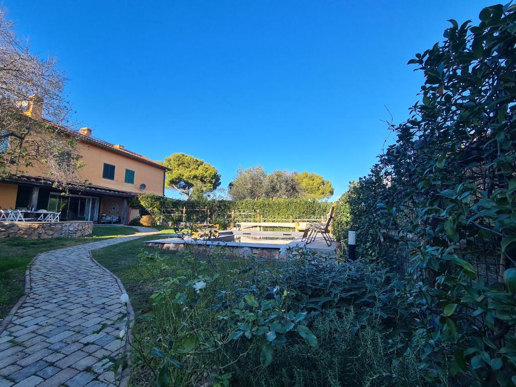 a garden with a stone path leading to a house at Portion of a villa with a private pool in Ansedónia